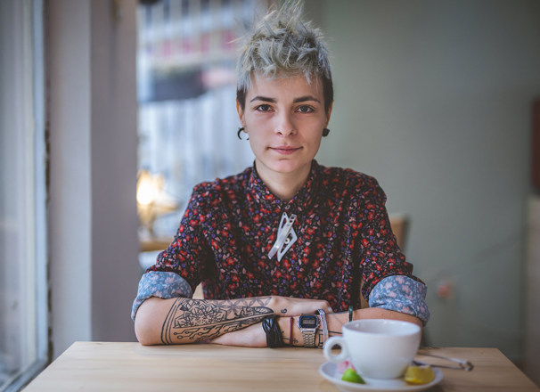 A portrait of a person sitting at a cafe table.