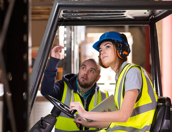 A forklift driver trains with another worker.