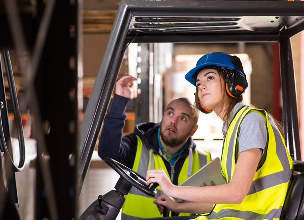 A forklift driver trains with another worker.
