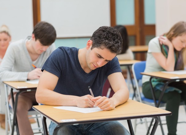 Post-secondary student writing exam at desk in a classroom.