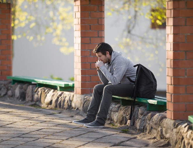 Mature student sitting anxiously outside of school.