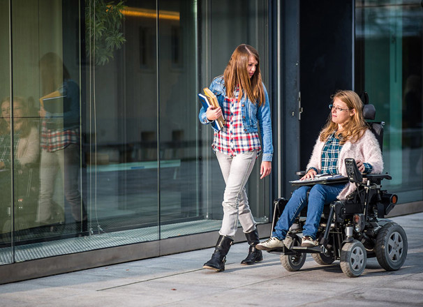 2 people walking down a sidewalk carrying books