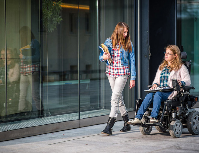 2 people walking down a sidewalk carrying books