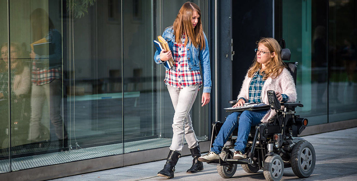 2 people walking down a sidewalk carrying books