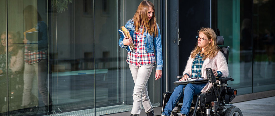 2 people walking down a sidewalk carrying books