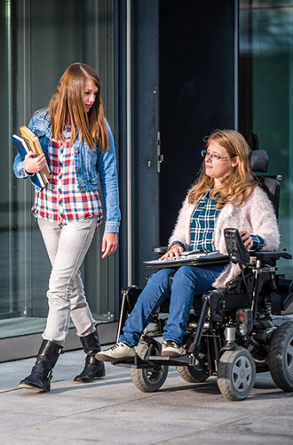 2 people walking down a sidewalk carrying books