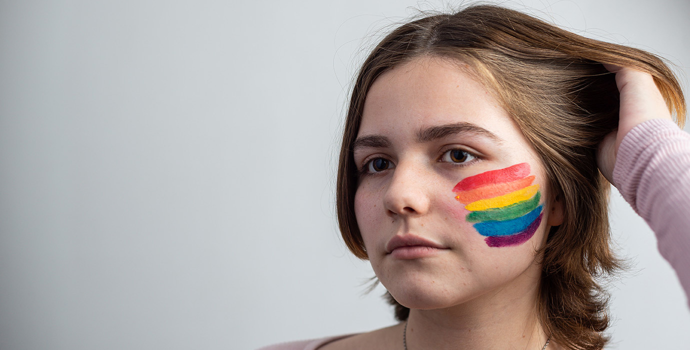 Person with a rainbow flag painted on their cheek