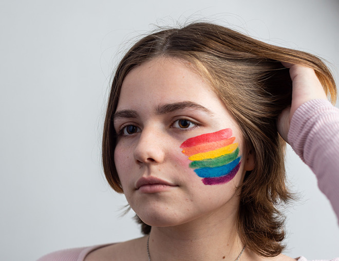 Person with a rainbow flag painted on their cheek