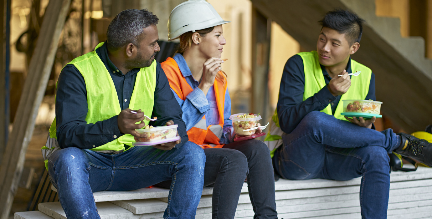 Three construction workers eating lunch on a jobsite.