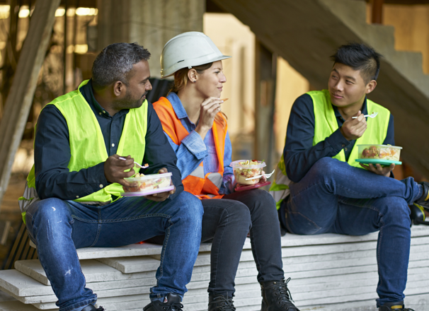 Three construction workers eating lunch on a jobsite.