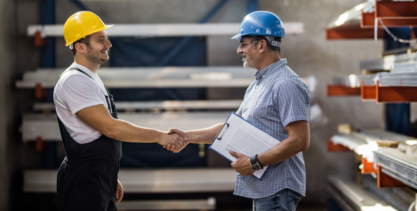 Two workers shaking hands in warehouse.