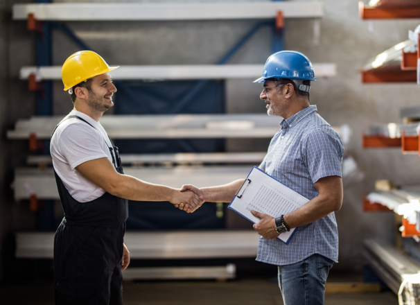 Two workers shaking hands in warehouse.