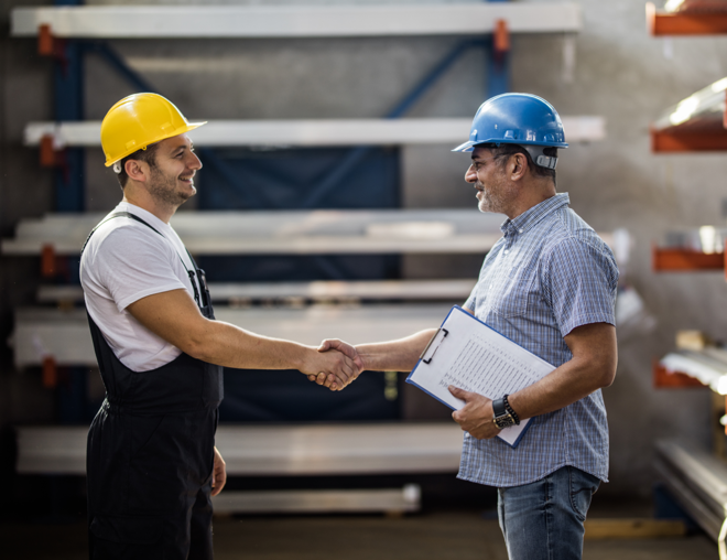 Two workers shaking hands in warehouse.