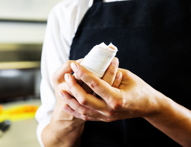 Chef holding injured finger in kitchen.