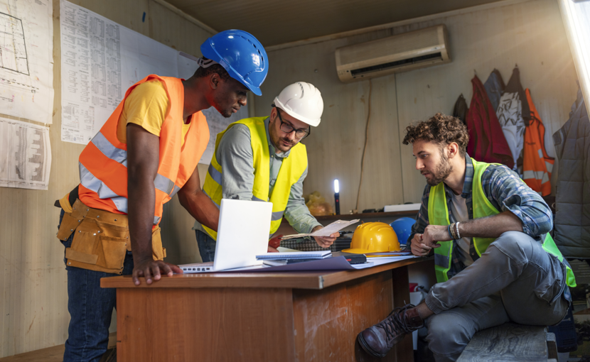 Workers around desk discussing project plans.