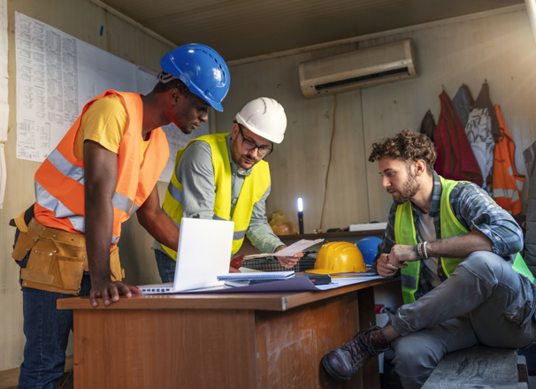 Workers around desk discussing project plans.