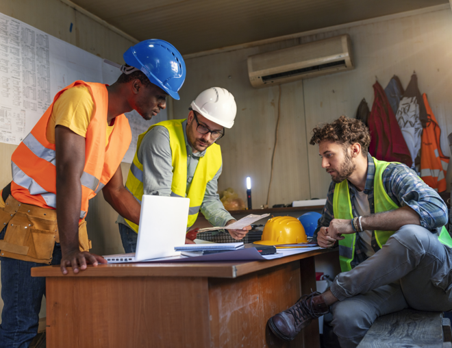 Workers around desk discussing project plans.