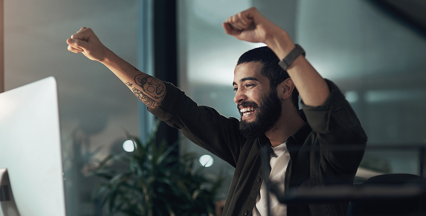 Person raising both arms up in celebration in an office