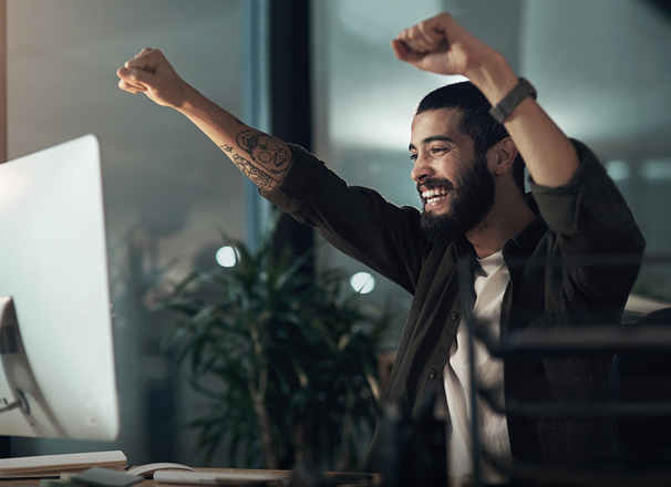 Person raising both arms up in celebration in an office