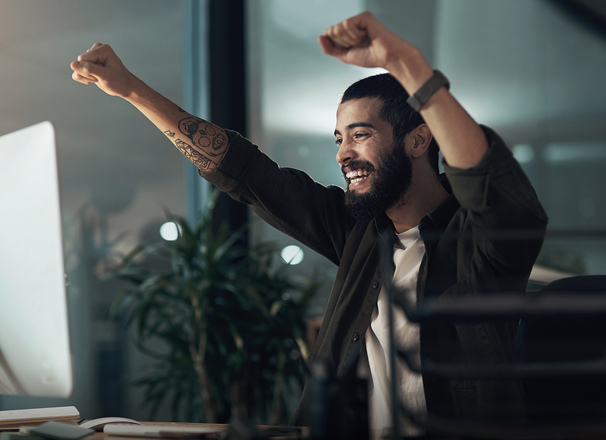 Person raising both arms up in celebration in an office