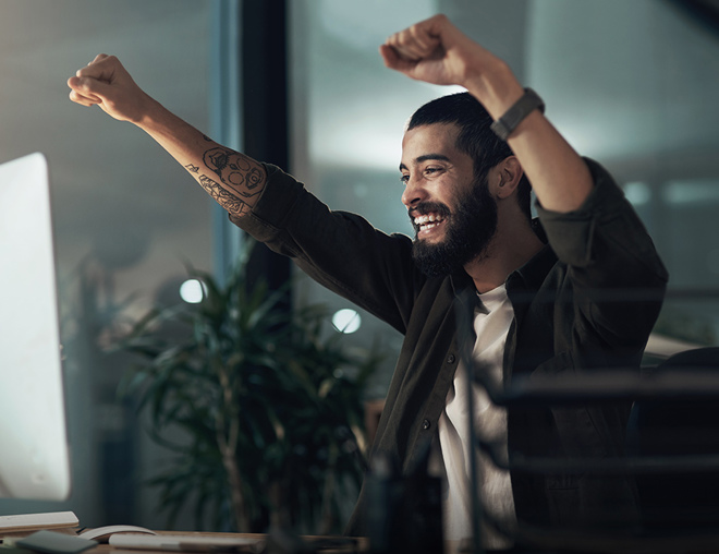 Person raising both arms up in celebration in an office