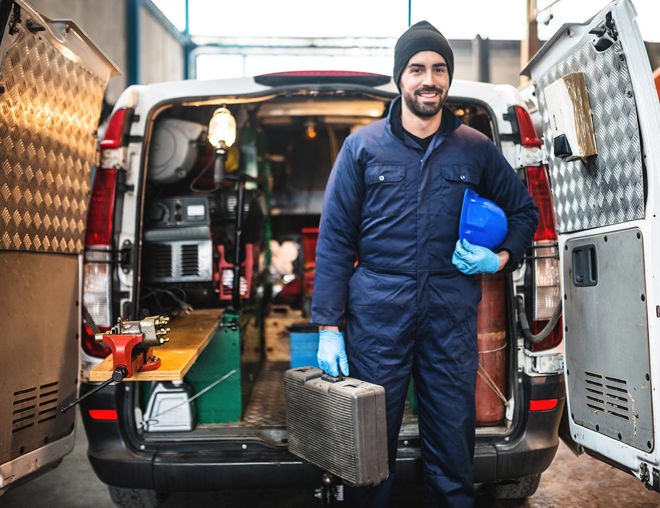 Mechanic standing in front of the opened back doors of a van