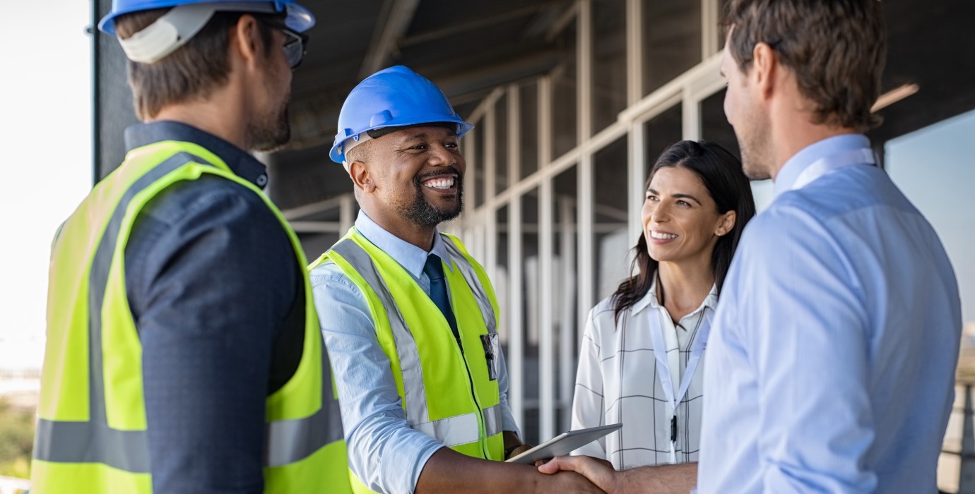 Workers shaking hands on a construction site.