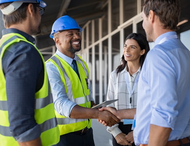 Workers shaking hands on a construction site.