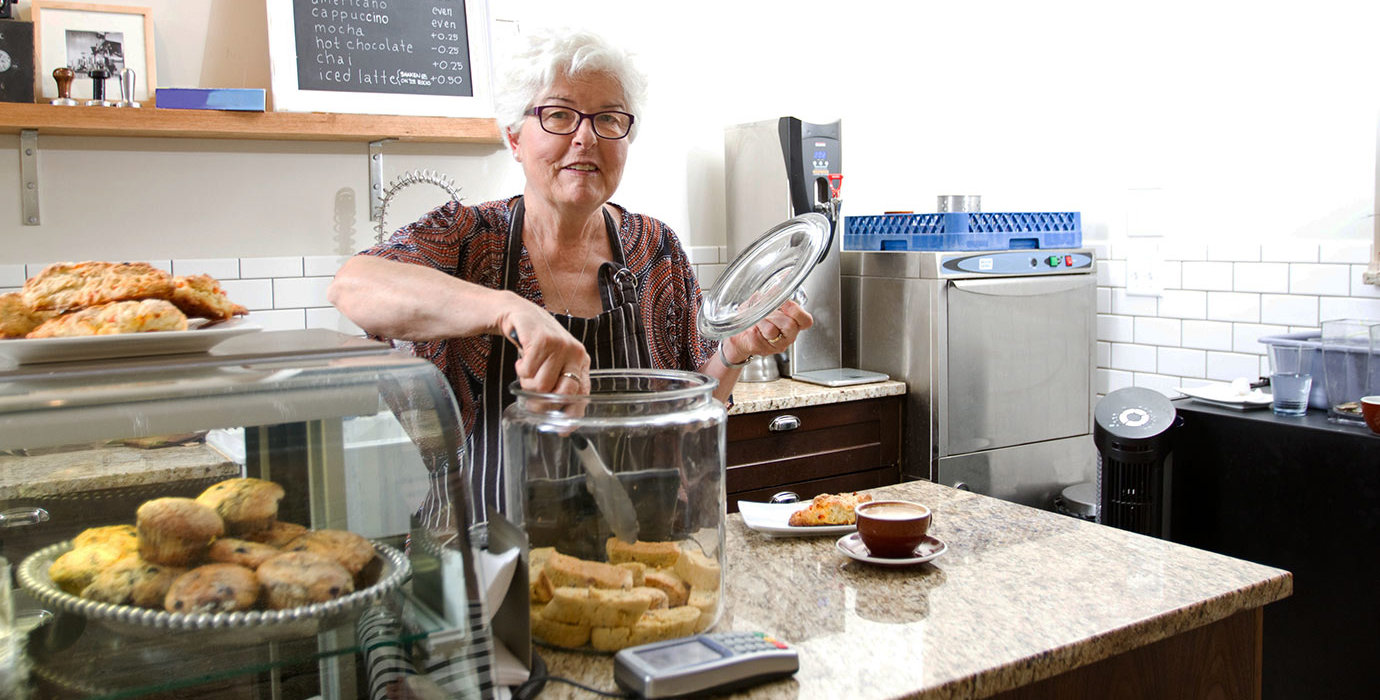 Person taking a cookie from a jar while working at a cafe