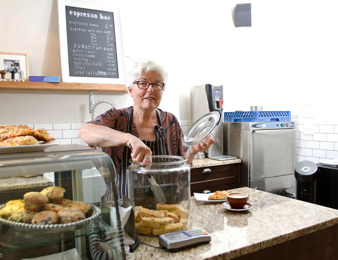 Person taking a cookie from a jar while working at a cafe