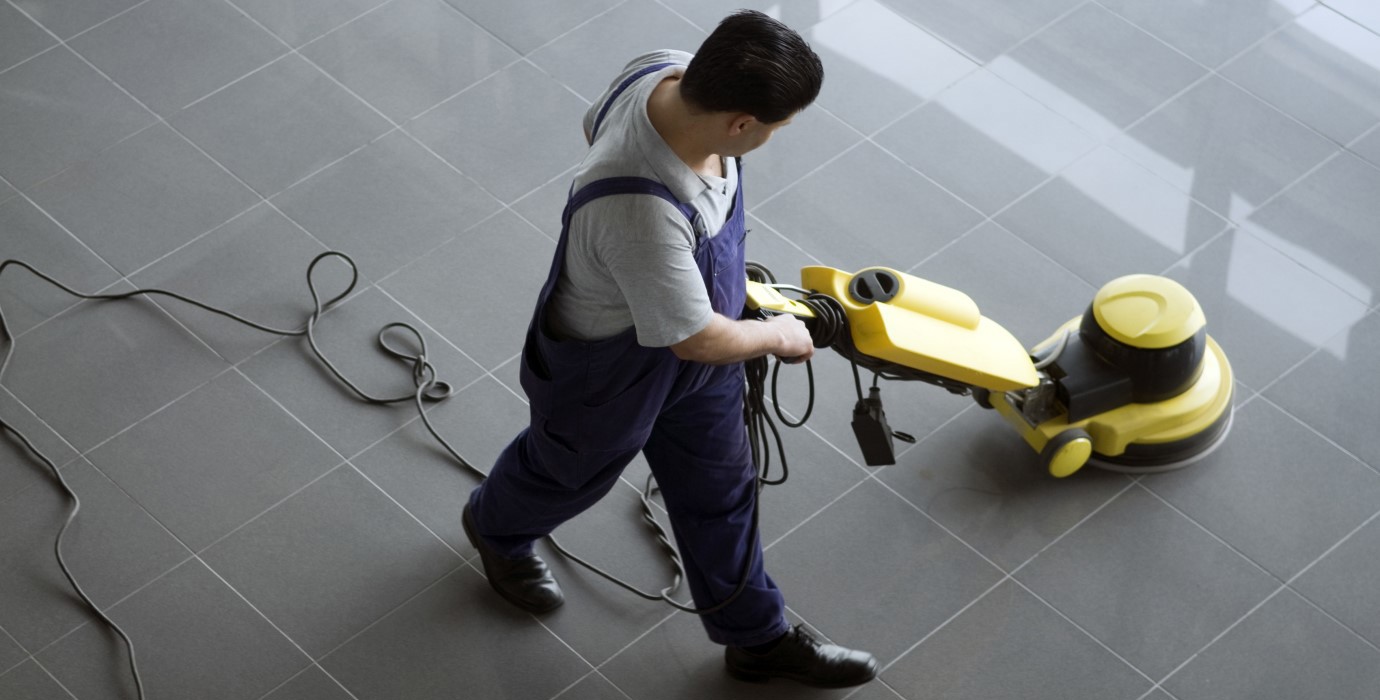 Person cleaning floor with electric floor cleaner.