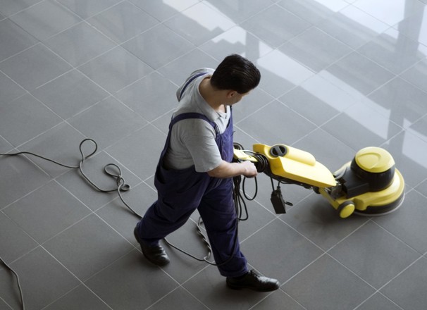 Person cleaning floor with electric floor cleaner.
