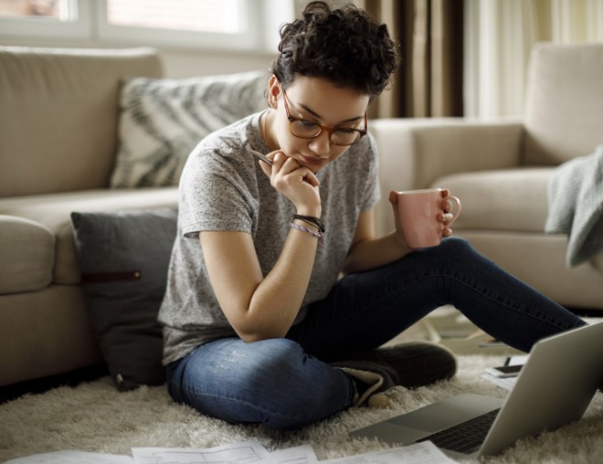 Person sitting on floor and using laptop.