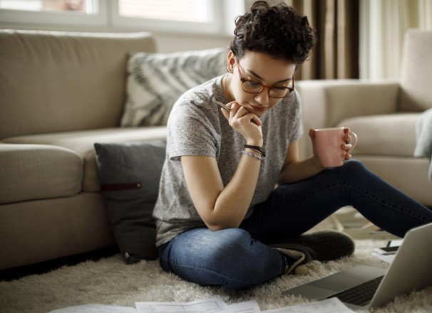 Person sitting on floor and using laptop.