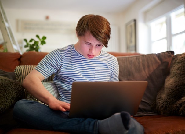 Person sitting on couch and looking at laptop. 
