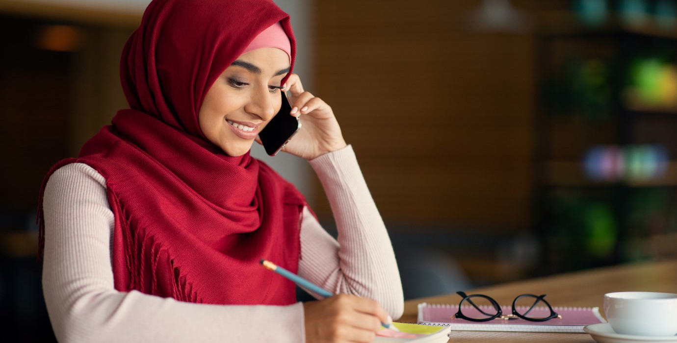 Person speaking on phone and taking notes. 