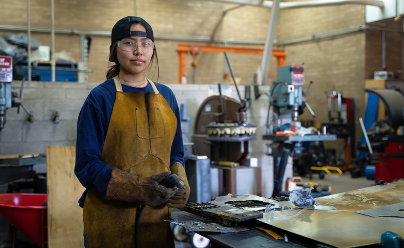 Young person working on sheet metal in a shop.
