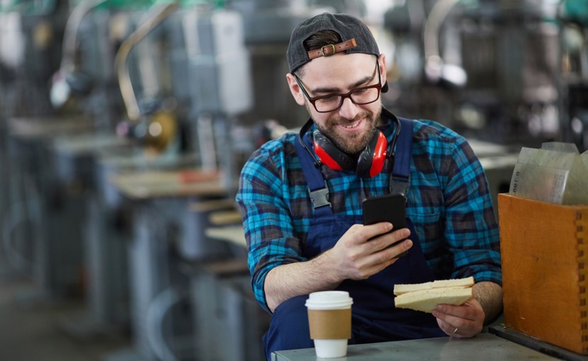 Person eating sandwich and drinking coffee on their break at a factory.