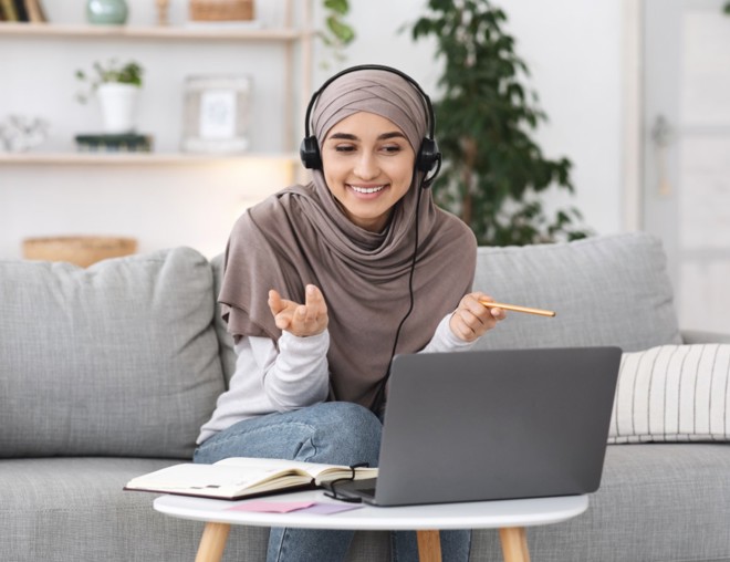 Person interviewing someone on laptop while sitting on couch.