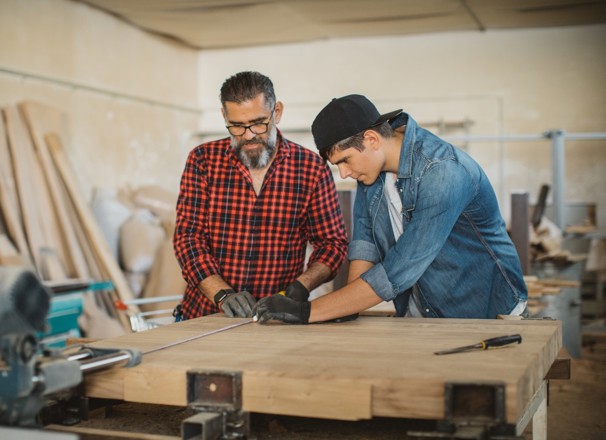 Father and son clamping wood in a carpenter's workshop.