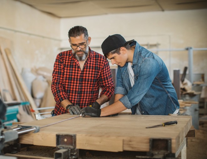 Father and son clamping wood in a carpenter's workshop.