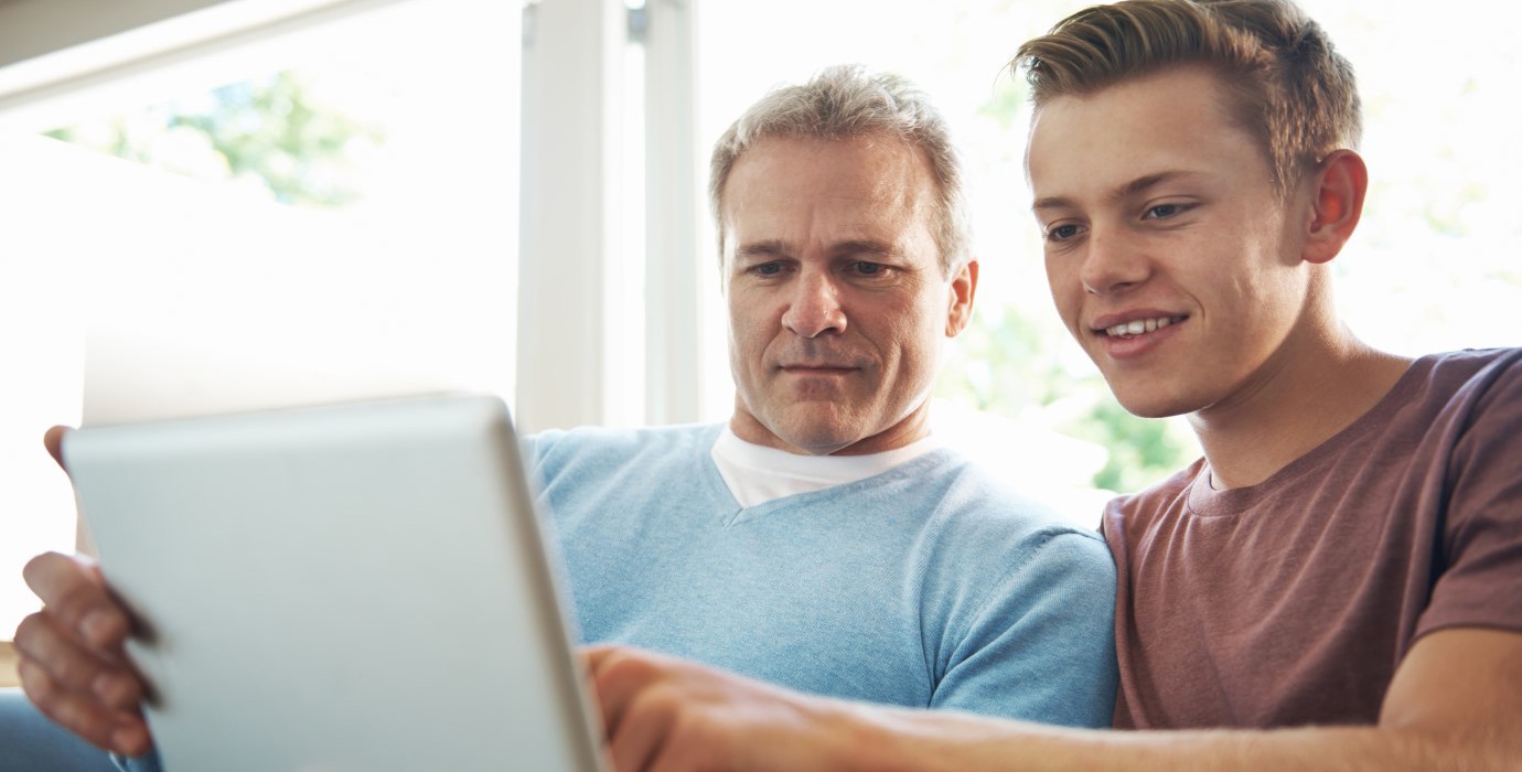 Father looking at a tablet with his son.