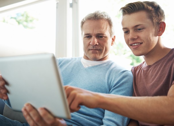 Father looking at a tablet with his son.
