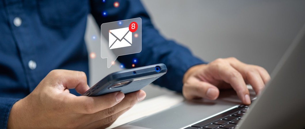 person emailing with a cellphone and a laptop