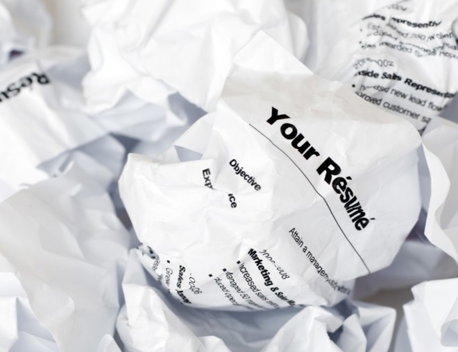 A crumpled resumé in a pile of rejected resumés.
