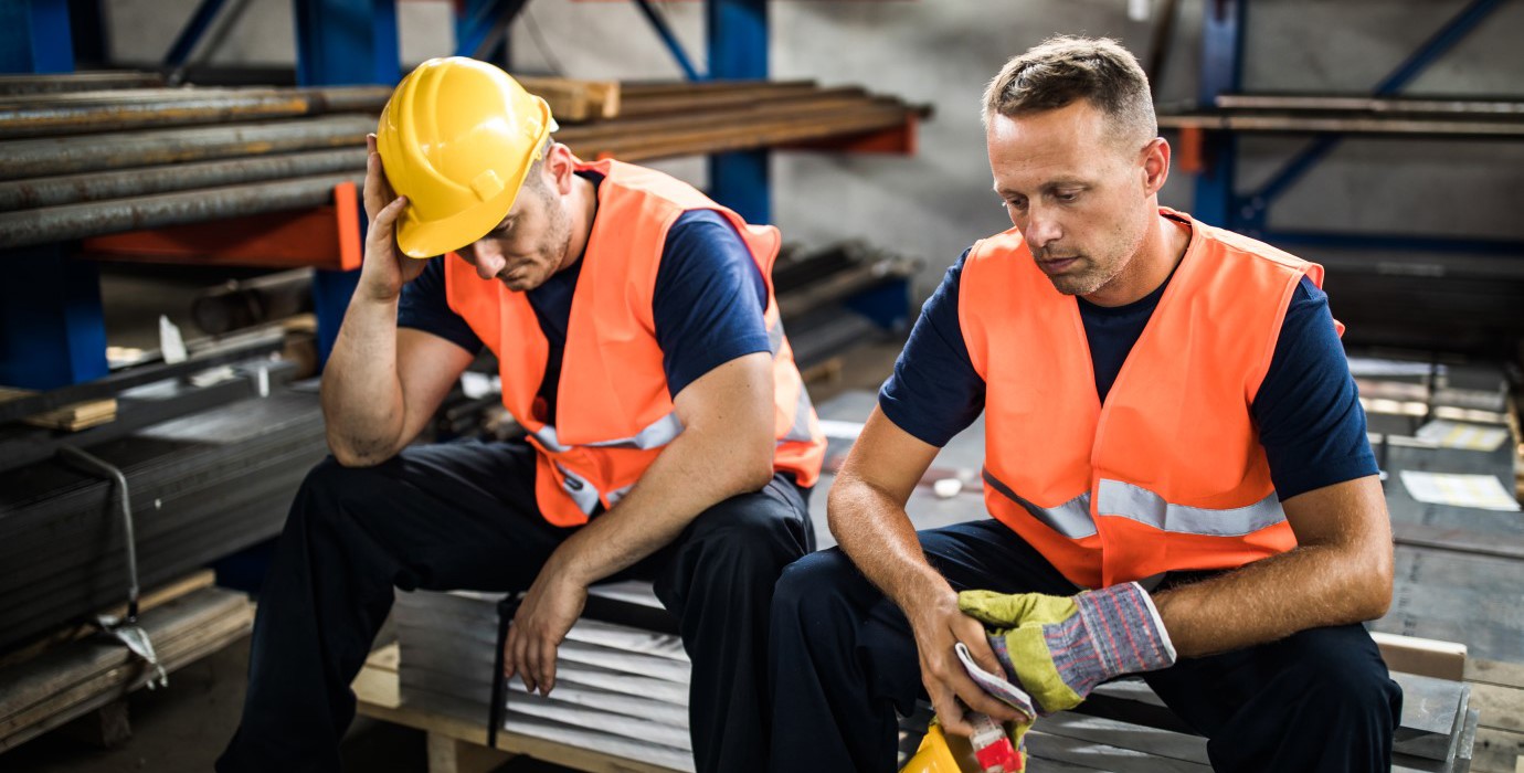 Two labourers sitting down and looking depressed.