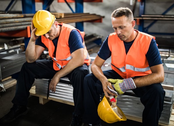 Two labourers sitting down and looking depressed.