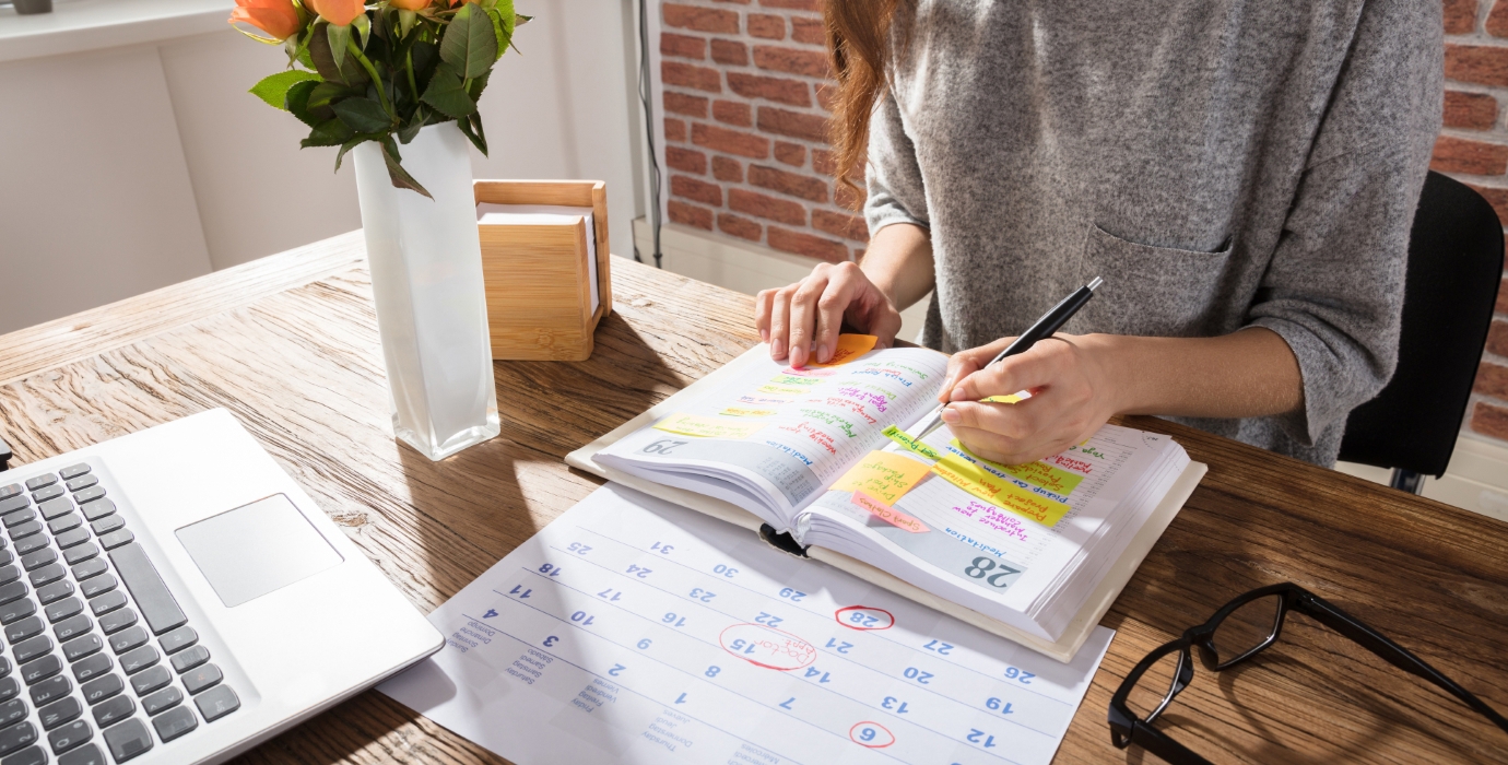 Person filling out weekly schedule on a calendar. 