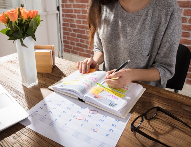 Person filling out weekly schedule on a calendar. 