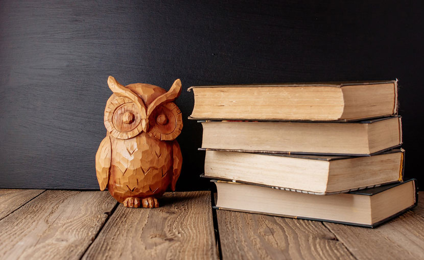 wooden owl next to stack of books